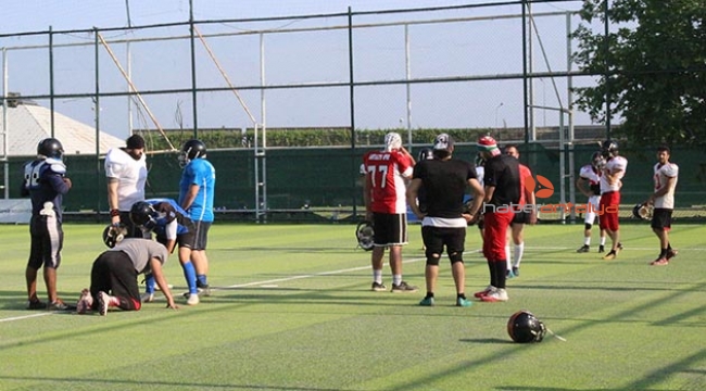 Futbol sahasında Amerikan futbolu oynuyorlar